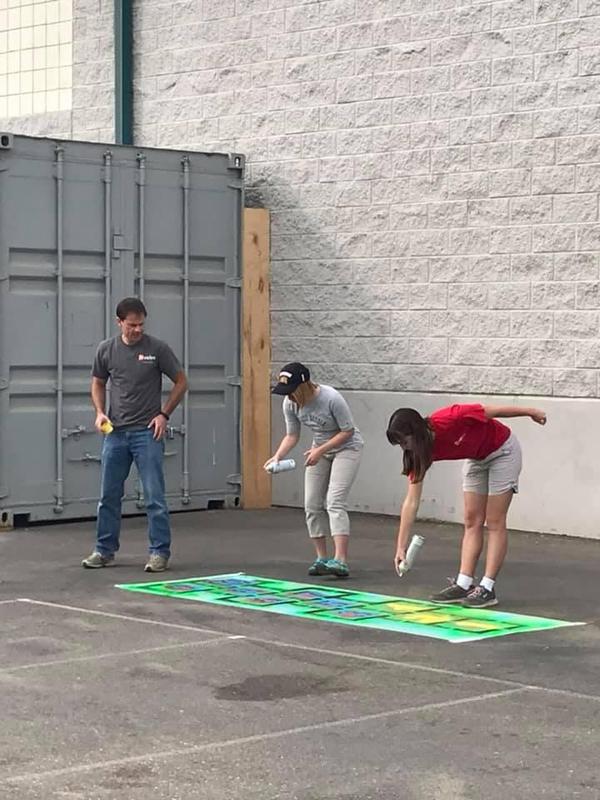 Volunteers spray paint a hopscotch game at Snake River Elementary.