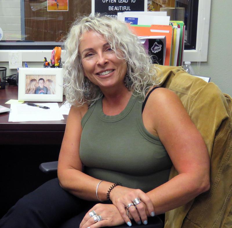Kat Armstrong sits at her desk with a framed family photo in the background.
