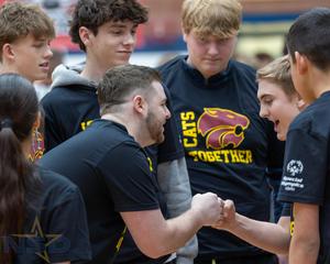 A player and coach bump fists, surrounded by supporters.