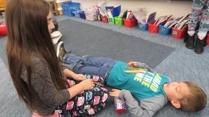 Two children act out the word \"bury.\"