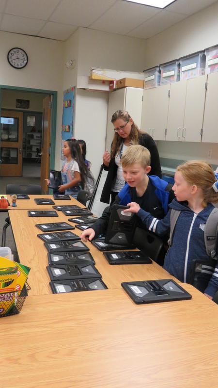 Students pick up their iPads before the Donut Hackers meeting begins.