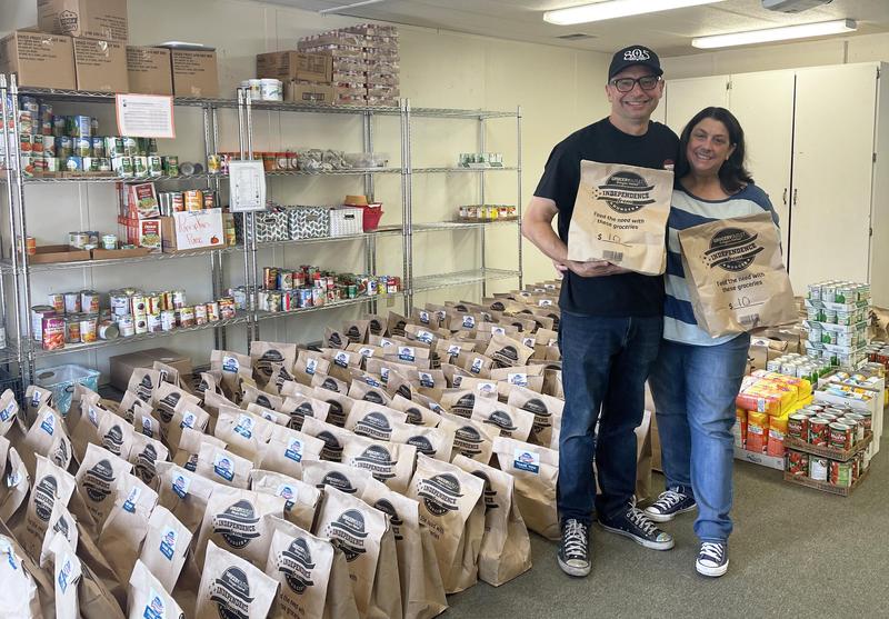 Danny and Shari Panasiuk stand amid dozens of food donation bags and canned goods.