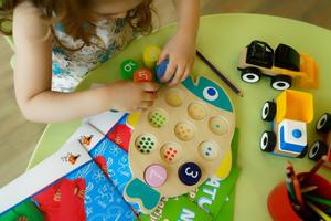 Overhead view of a young girl putting together a number puzzle on a bright-green table.