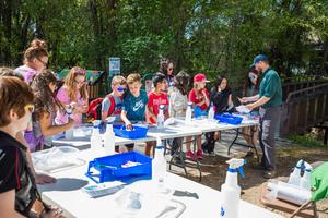 Students work at a project at folding tables along Wilson Creek.