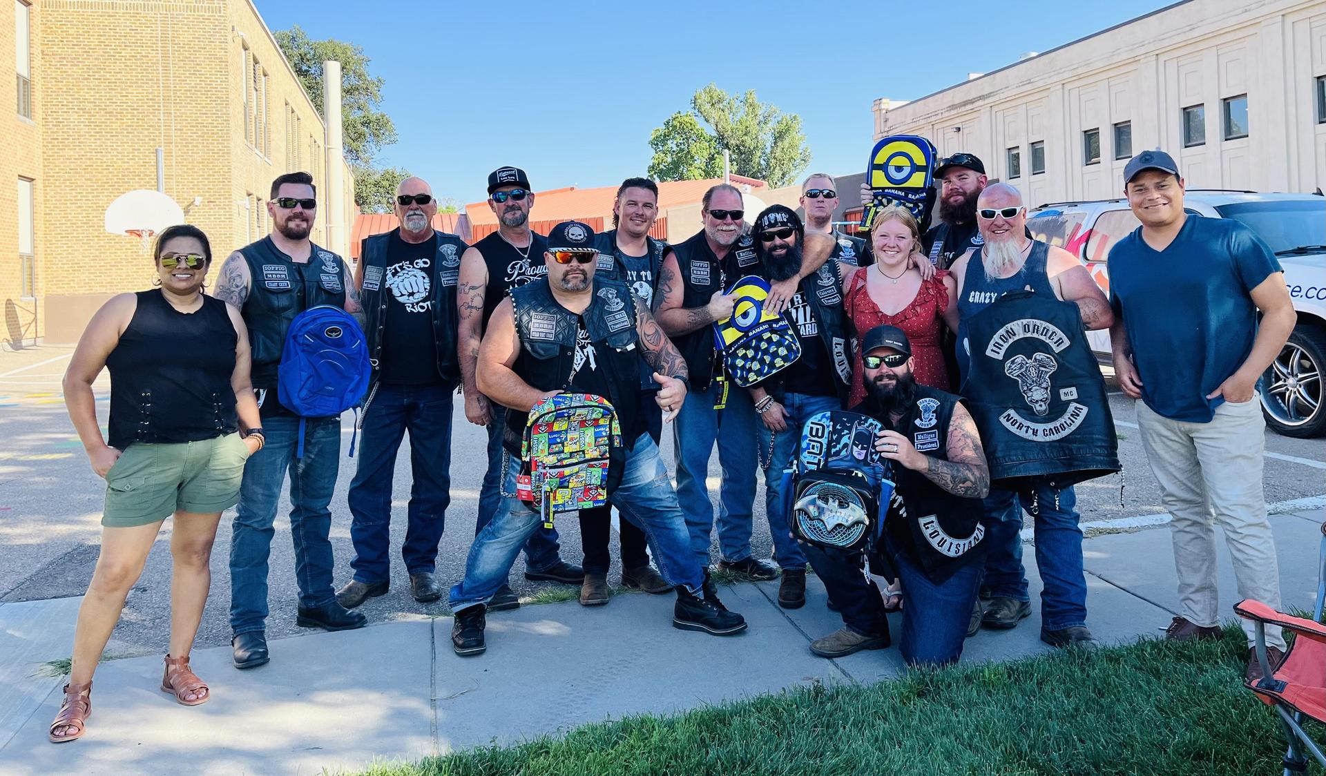 Bikers pose in leather vests in front of Central Elementary with donated backpacks.