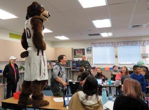 University of Montana mascot stands on top of a desk while kids laugh.