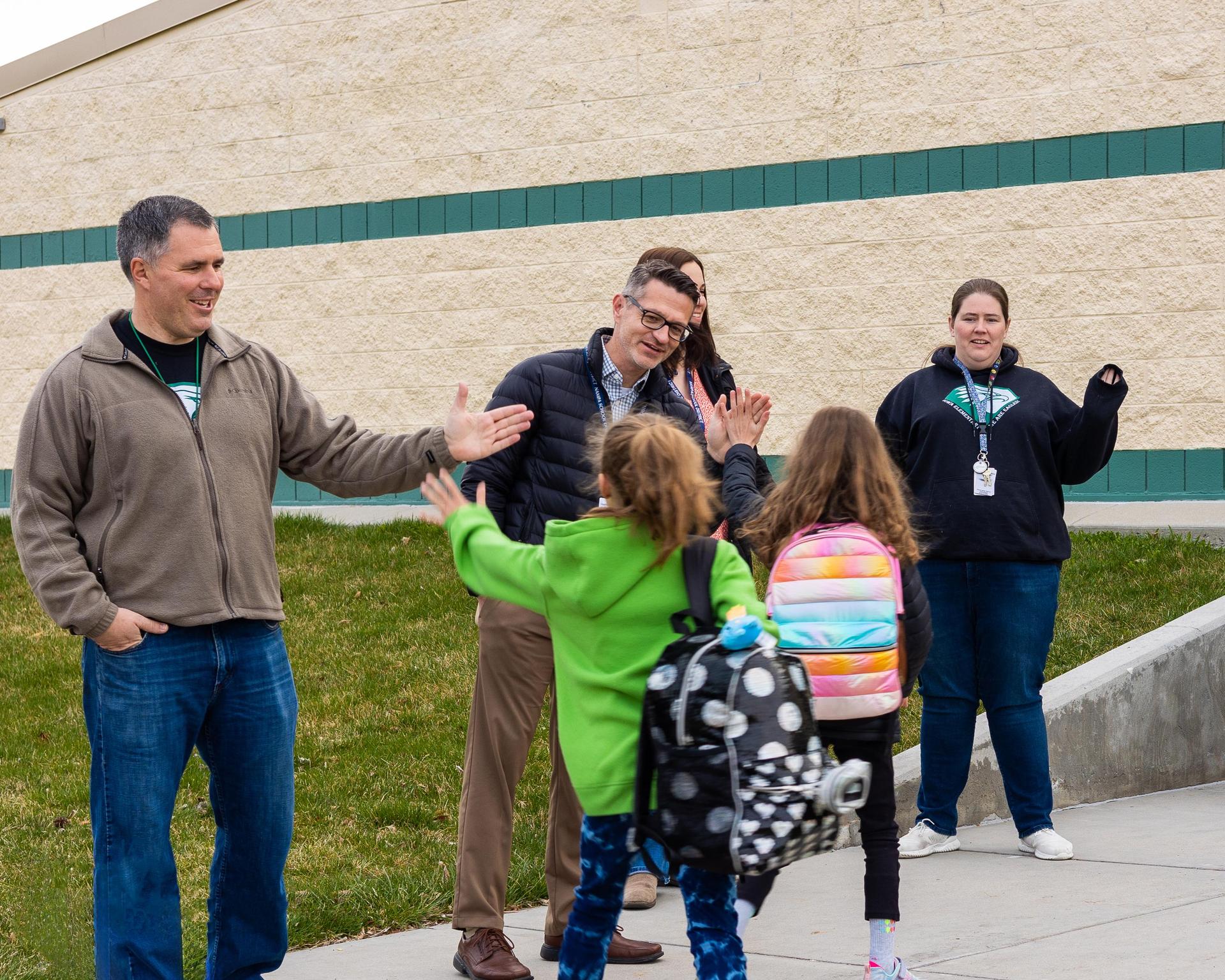 Boy walks through two rows of outstretched hands receiving high fives.
