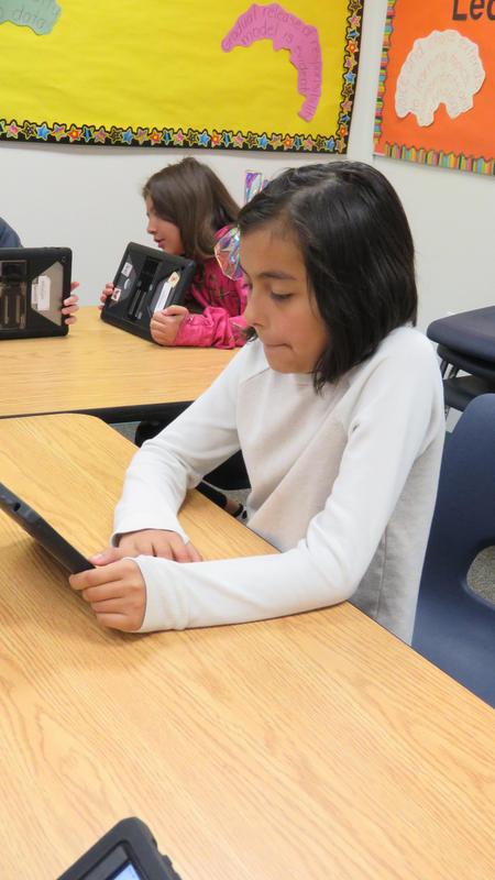 A girl works on her iPad at her desk.