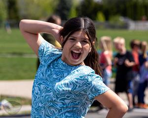 Girl in blue shirt strikes cheesy pose for the camera at field day.