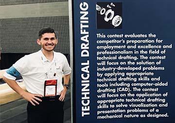 Ben Campbell stands in front of a Technical Drafting banner at the SkillsUSA competition.