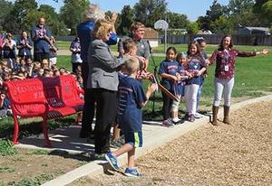 Children celebrate cutting the ribbon on their new bench.