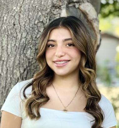 Natalie Coronado poses in front of a tree.
