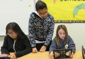 Three girls work on their iPad apps.