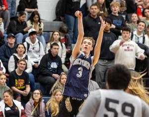 A male special education athlete in a Skyview jersey has both hands raised after throwing a basketball.