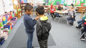 Two boys act out a vocabulary word in front of the class.