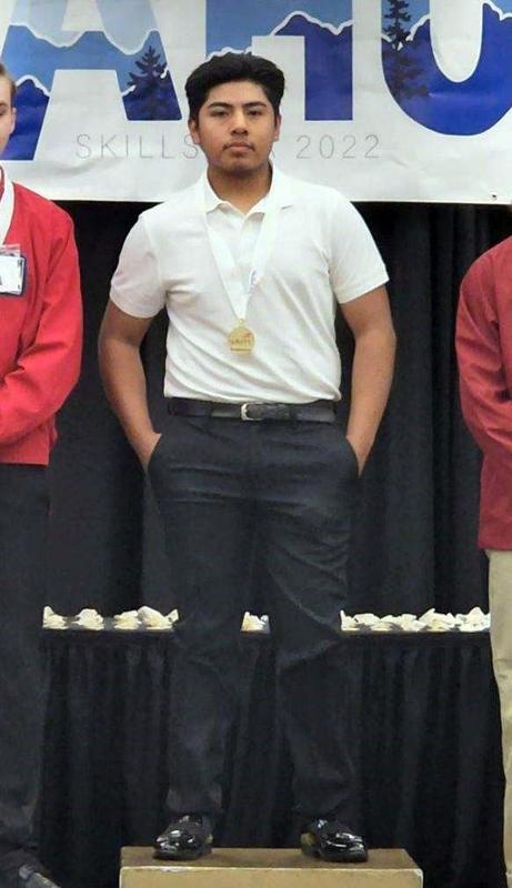 Luis Martinez Cruz stands on the winner\'s podium wearing a white polo shirt, with hands in his pants pockets.