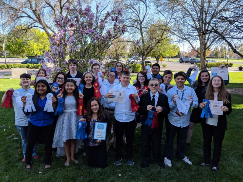 Group photo of speech and debate championship team with ribbons.