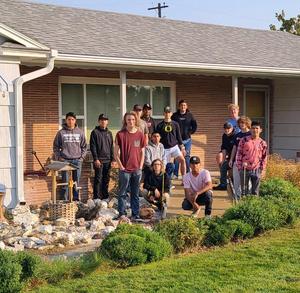 Construction students pose in front of the home where they built a ramp.