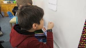 A boy pretends to look through a magnifying glass.