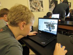 Young boy concentrates on an image of a space station on his laptop screen.
