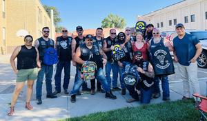Bikers pose at Central Elementary in their leather vests, holding donated backpacks.