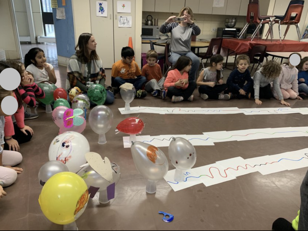 Small robots are covered up by plastic cups decorated with balloons.