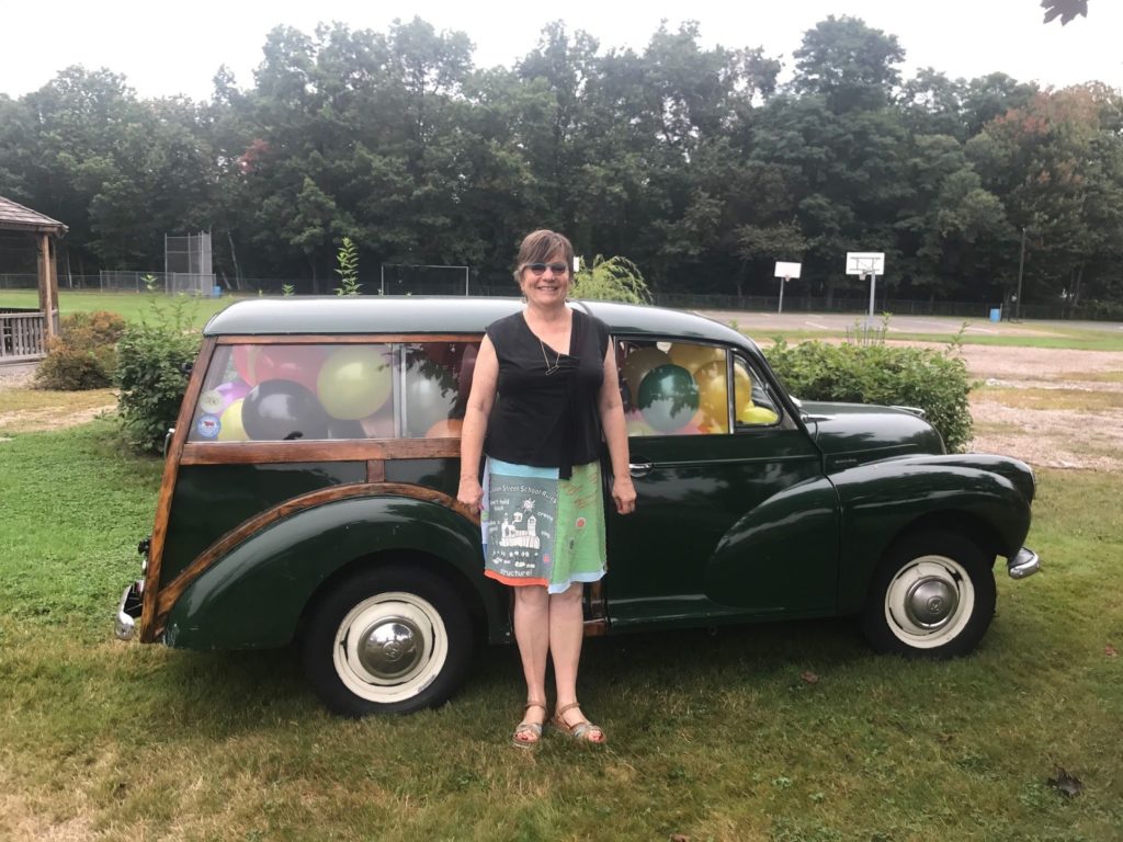 Gwen Agna standing in front of an old car filled with baloons.