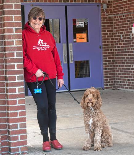 Gwen Agna with Jackson the dog standing in front of the Jackson Street School main entrance.