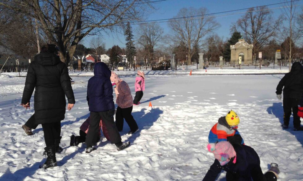 Kids kneeling and standing in the snow building beaver dams