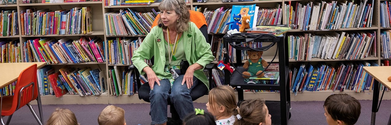 librarian sitting in a chair to read to children