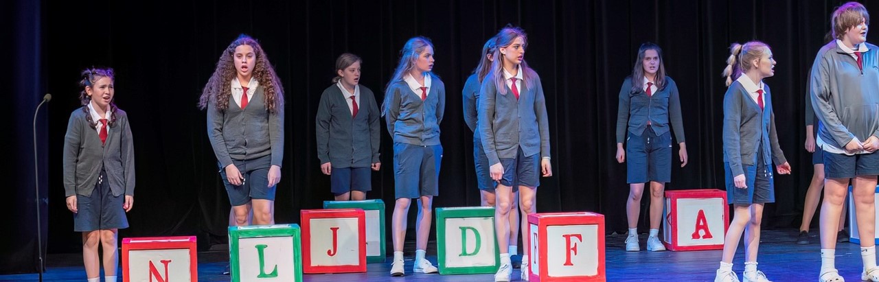 students from Matilda the Musical by large letter blocks