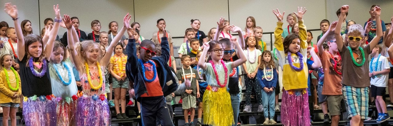 second-grade students wearing leis and dancing onstage