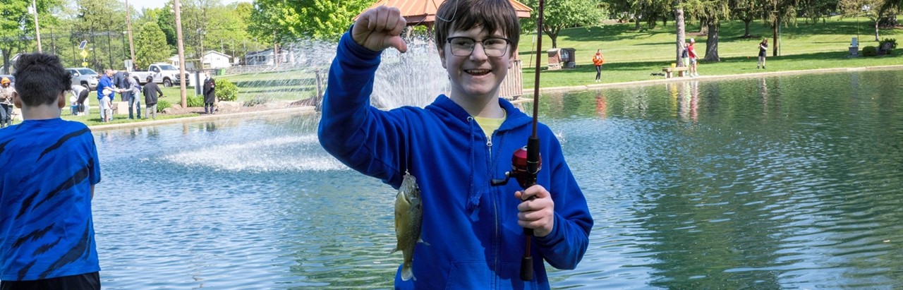 young boy shows the fish he caught