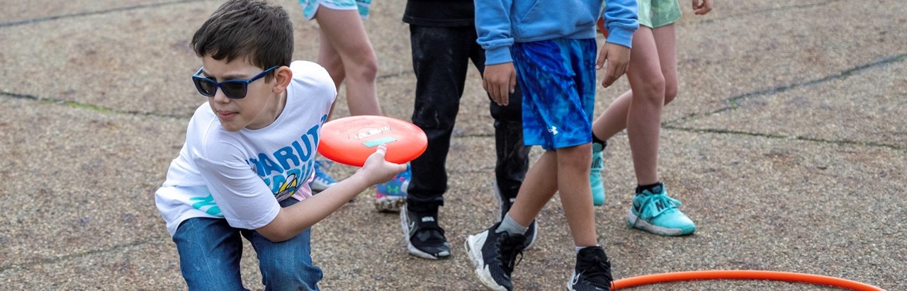 fourth-grade boy in sunglasses throws frisbee