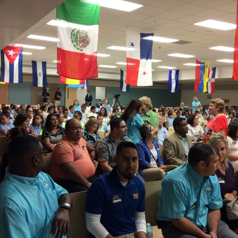 Room of people at dedication of 8 new and renovated elementary schools