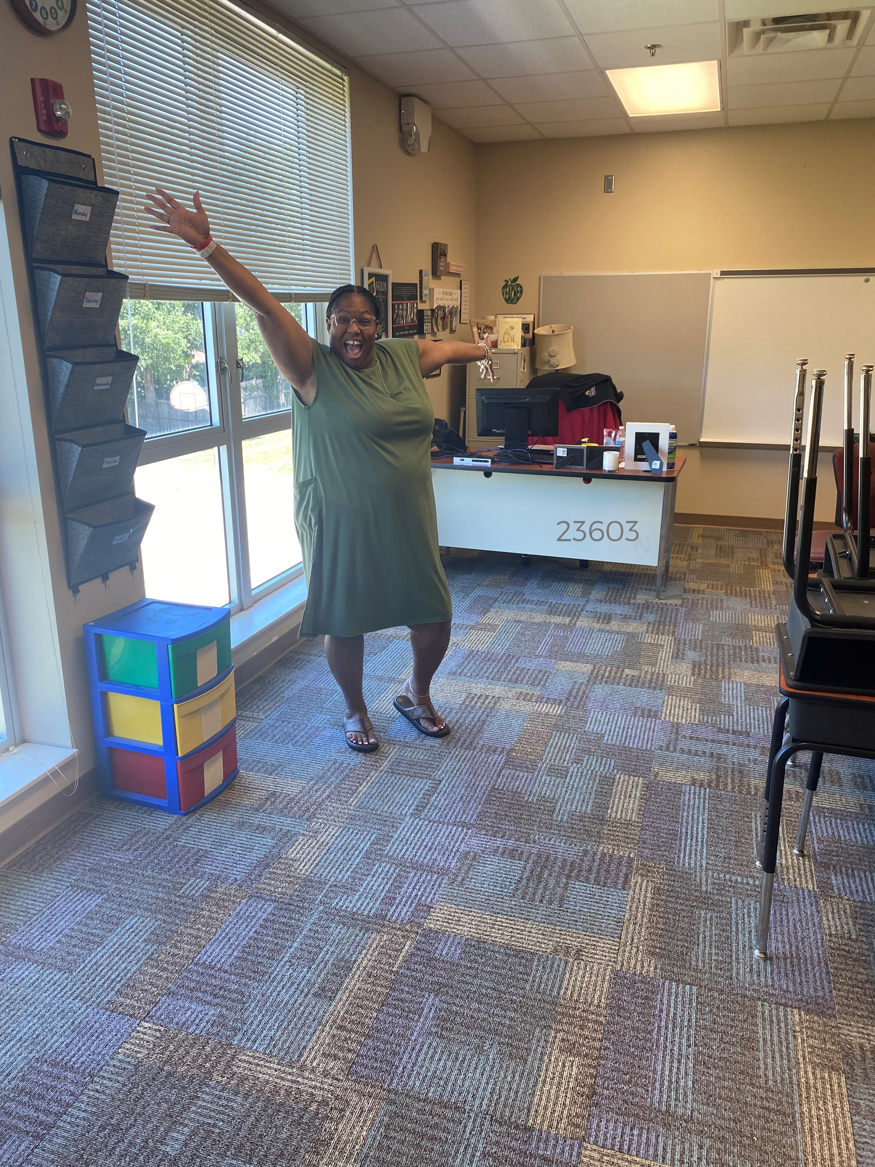 Jill Robbins standing excitedly on her new classroom carpet