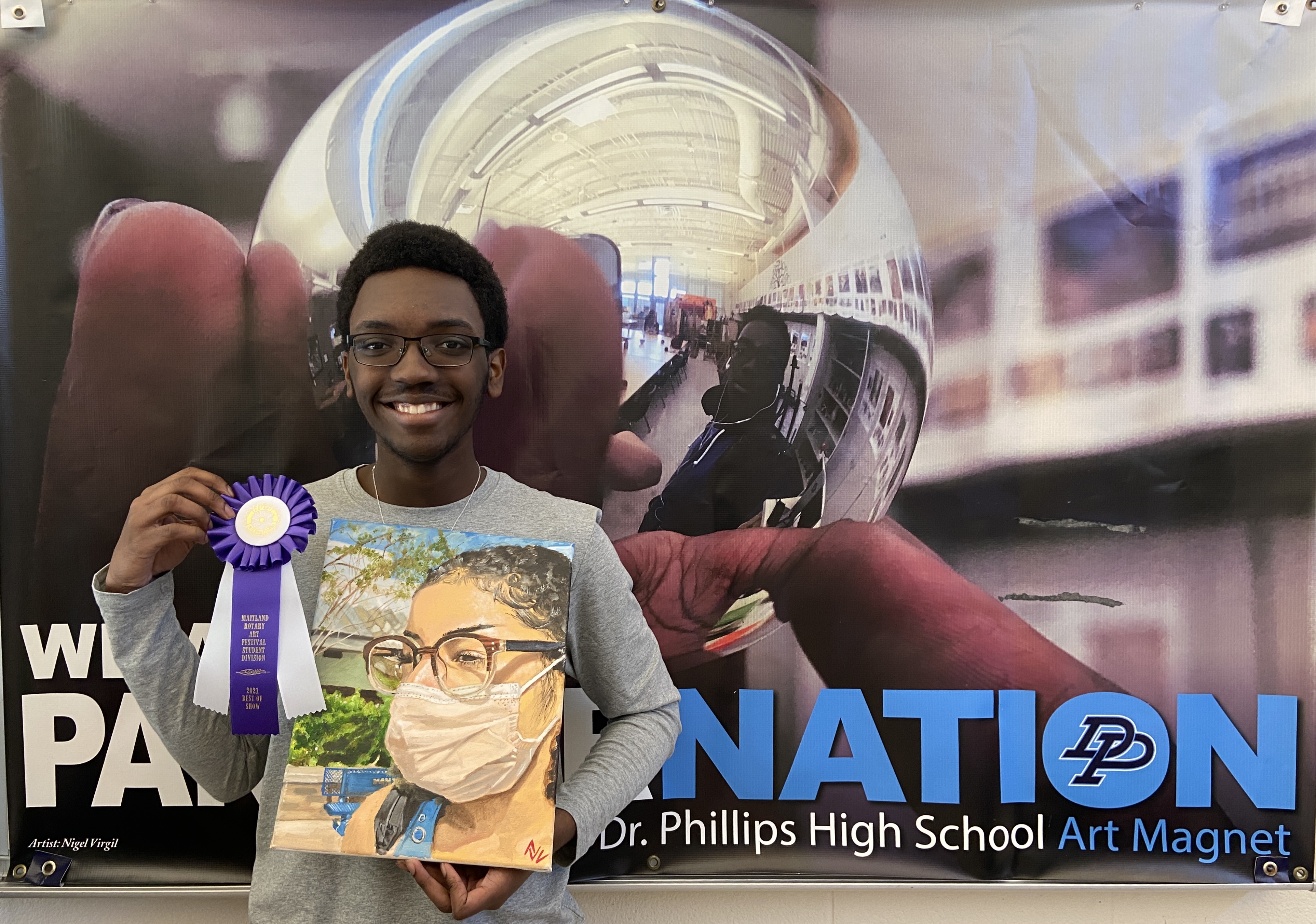 Student holding award ribbon and artwork