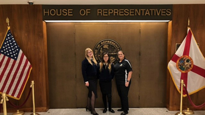 3 people pose in front of House of Representatives chamber doors