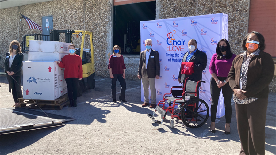 7 people spaced around a wheelchair being donated