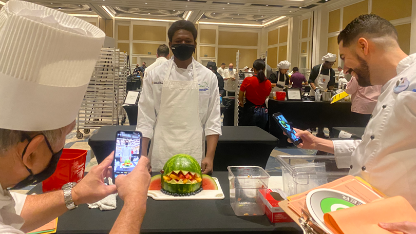 Student poses with fruit sculpture