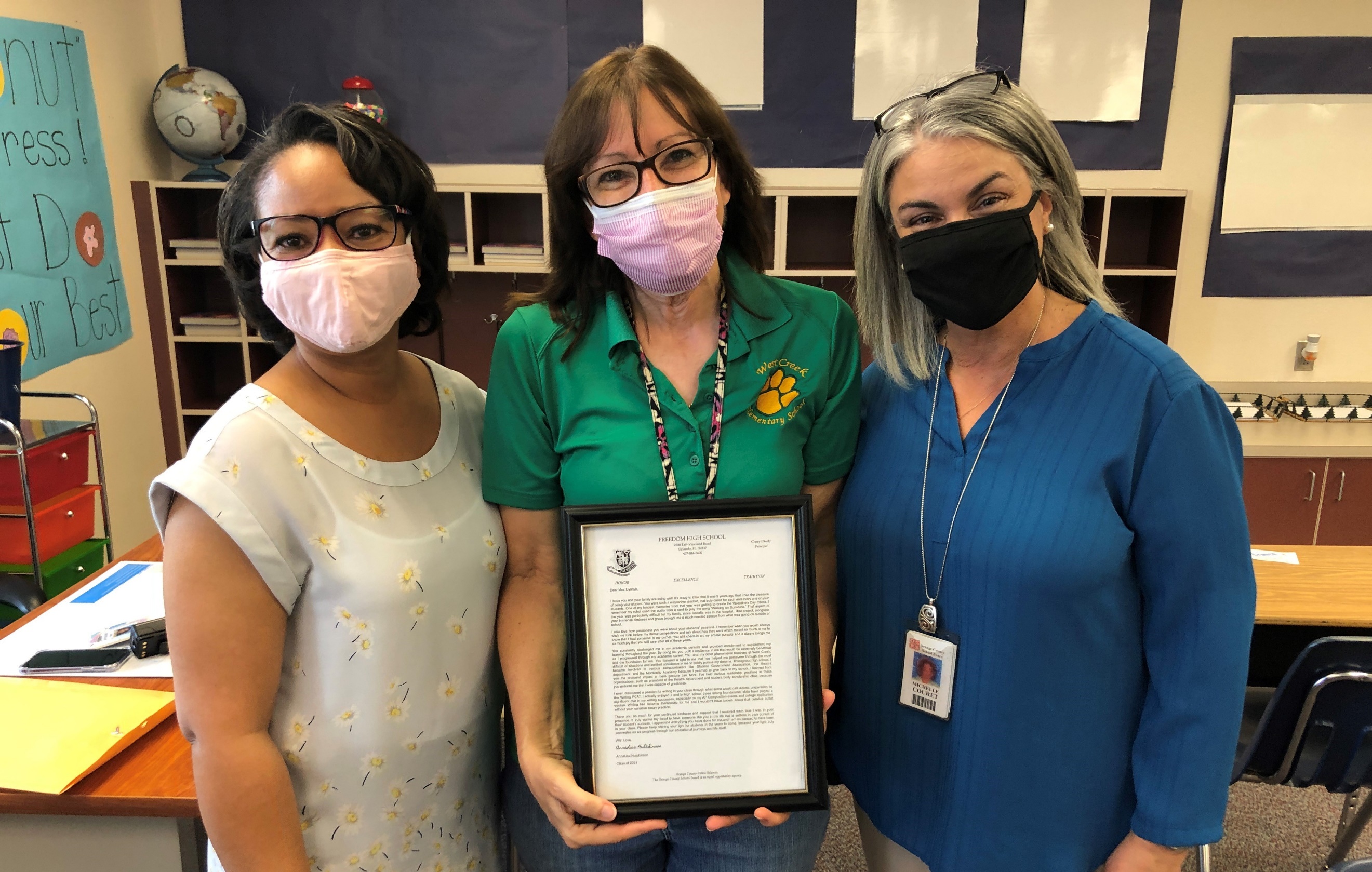 Ms. Hutchinson, Ms. Dyshuk, Ms. Couret hold a framed letter