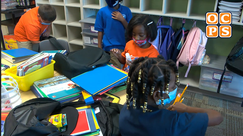 Students pull school supplies out of donated backpack