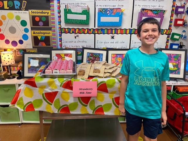 Student smiles in front of table of cookies