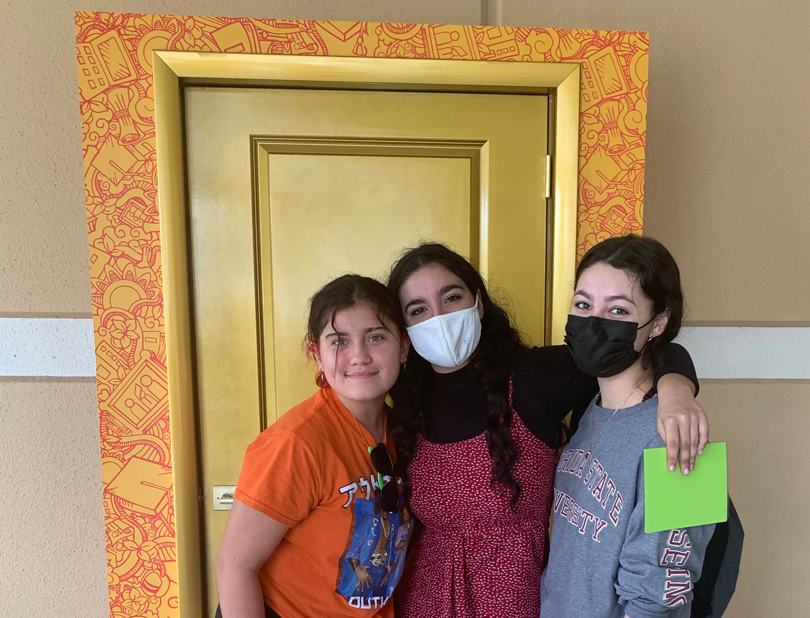 3 girls pose in front of the golden door