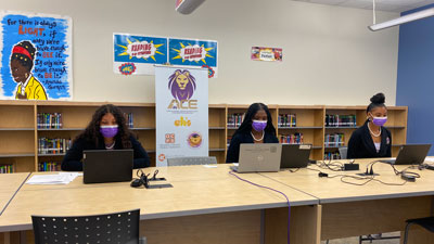 3 girls looking into laptops