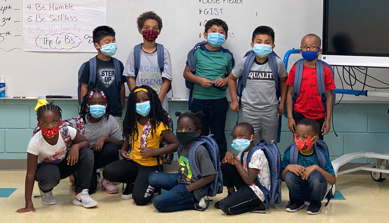 A group of students poses with their new backpacks