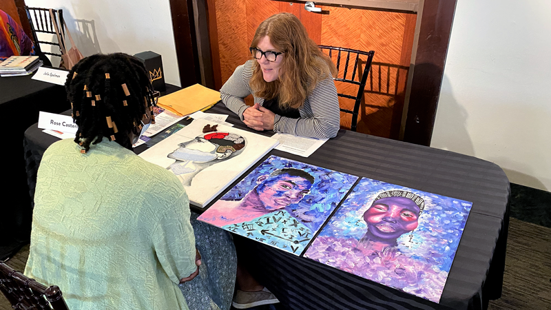 A teacher talks to a student about her art portfolio 