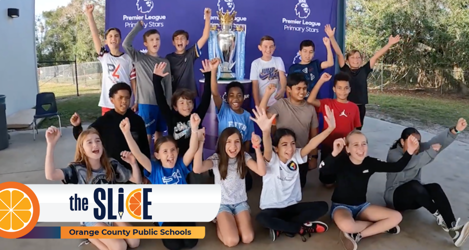 A group of students cheers in front of a trophy