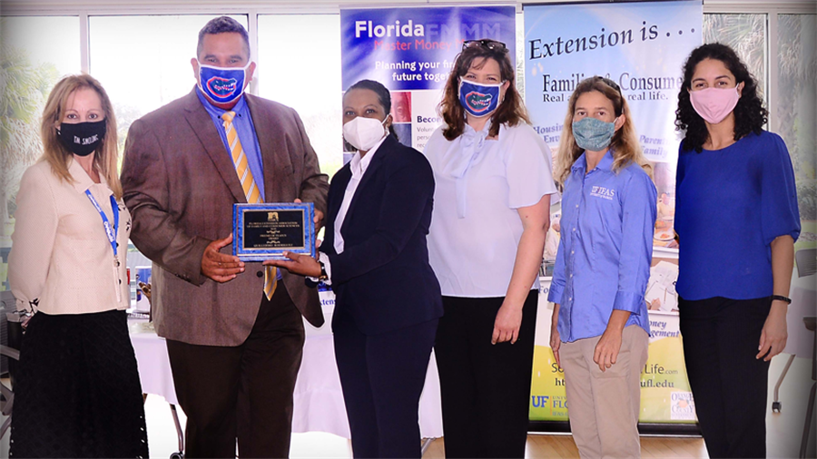 Six people wearing masks stand side by side for a group photo