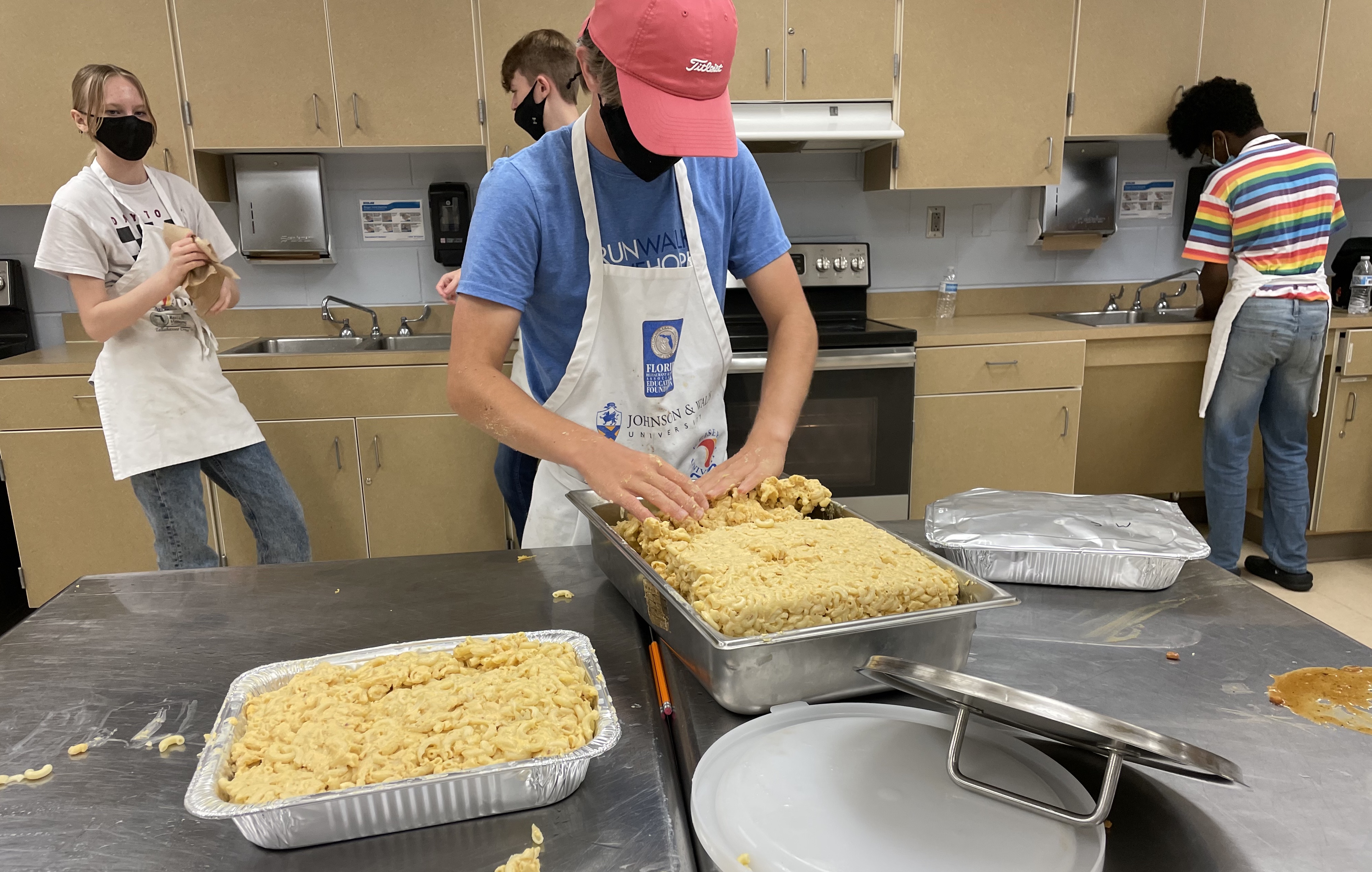 Male student organizes mac and cheese in catering pan